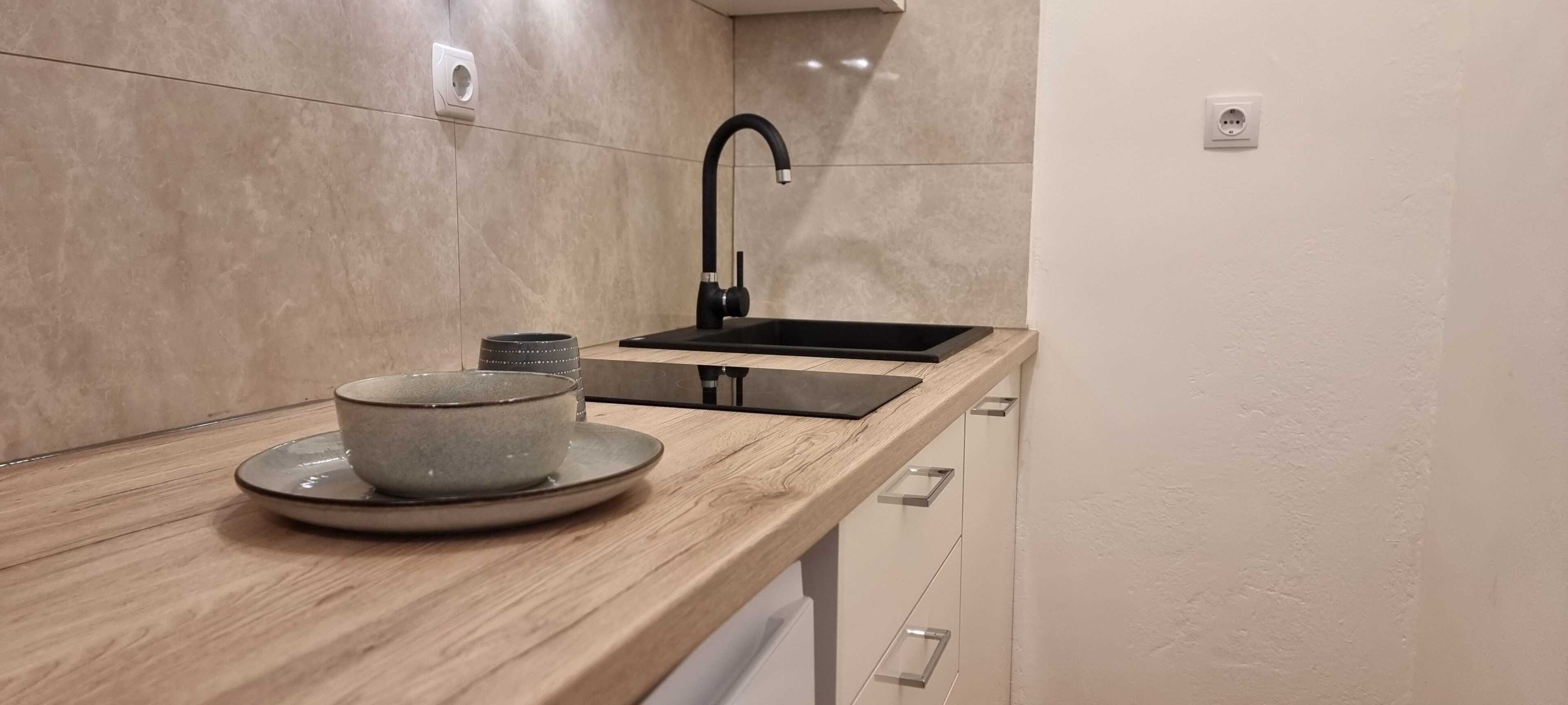 A modern kitchen with a wooden countertop, a sink, and a cup on a saucer.