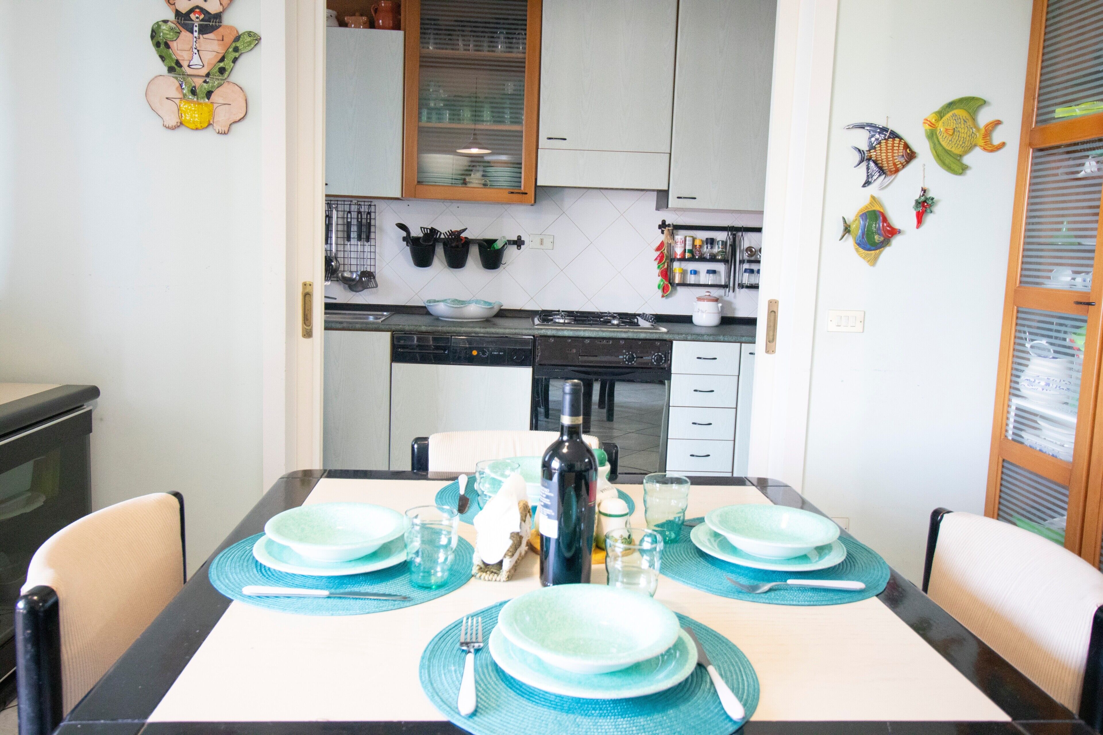 A dining table set with plates, glasses, and cutlery, a bottle, and a bowl.