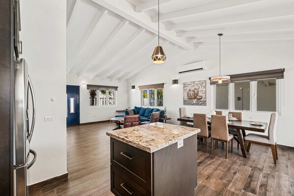 A spacious kitchen with a central island, a dining area with a table and chairs, and a living area with a sofa and coffee table. - Safir 48 (Noord)