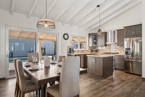 A modern kitchen with a central island, stainless steel appliances, and a dining area with a table and chairs.