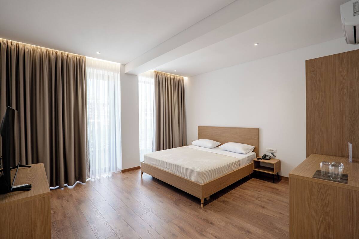Una habitación de hotel con una cama de madera, un escritorio y un armario.