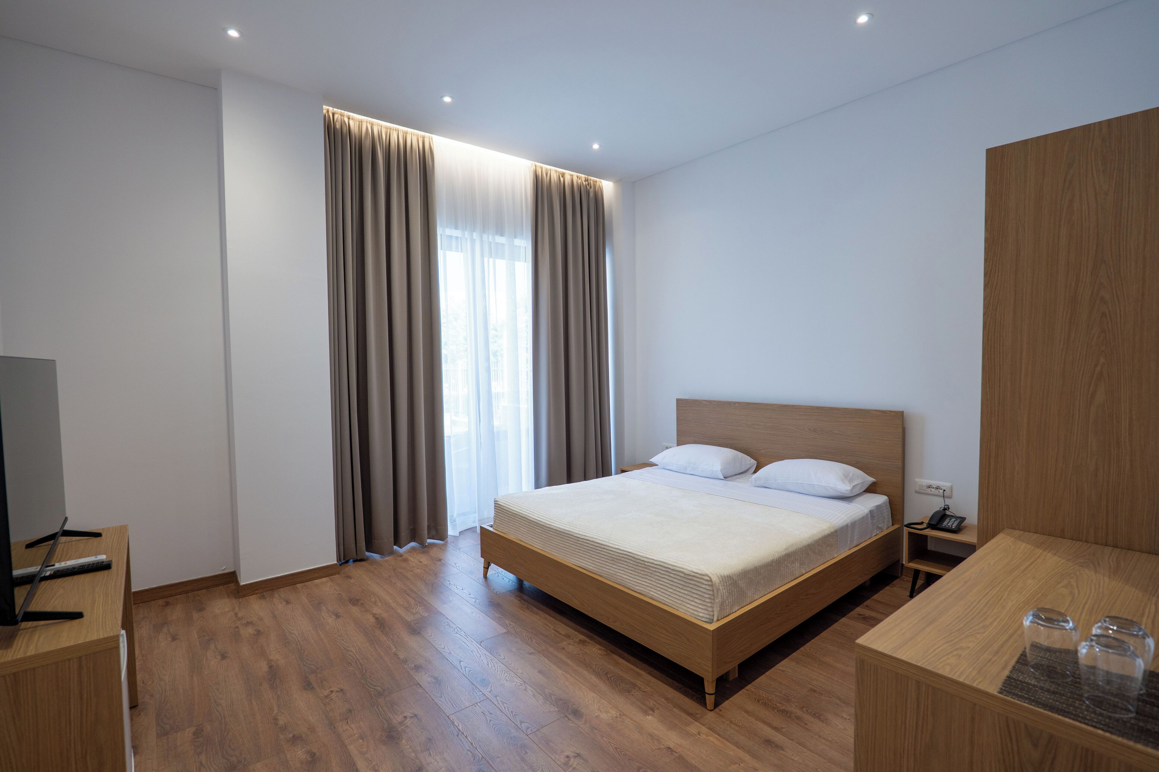 Une chambre d’hôtel moderne avec un lit en bois, une table de chevet avec une lampe et un téléviseur.