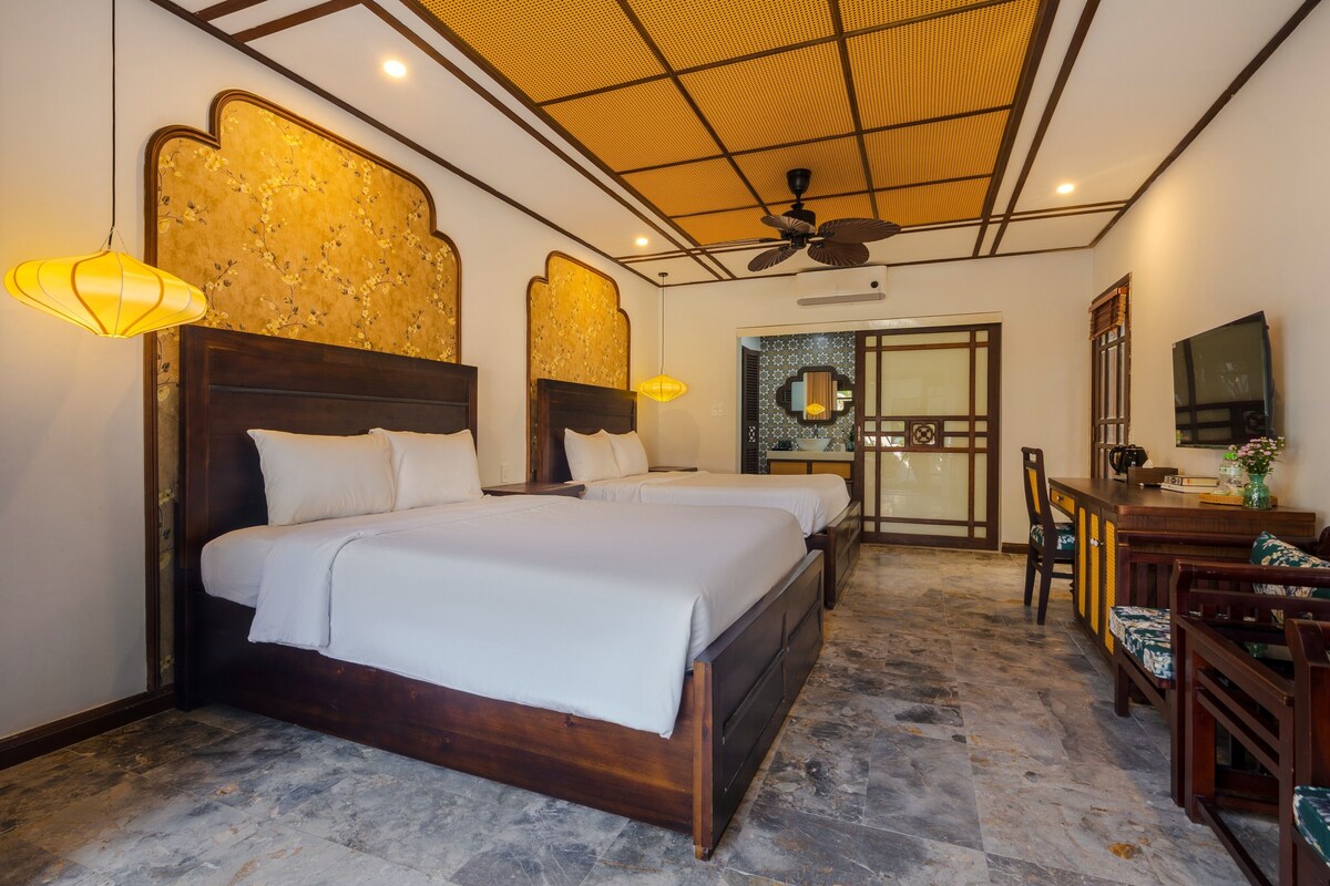 A hotel room with a large bed, a desk, a chair, and a ceiling fan.