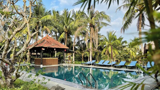A pool surrounded by palm trees, a covered seating area, and lounge chairs. - Ancient Retreat Hoi An (Da Nang)