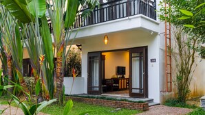 A modern two-story building with a balcony, a brick pathway, and lush greenery. - Ancient Retreat Hoi An (Da Nang)