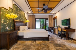 A hotel room with a bed, wooden dresser, desk, and a ceiling fan. - Ancient Retreat Hoi An (Hoi An Dong)