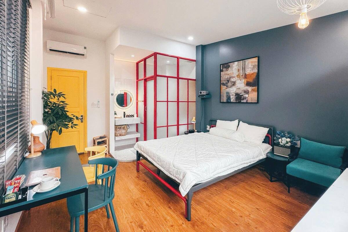 A modern bedroom with a bed, bedside table, and a desk with a chair.