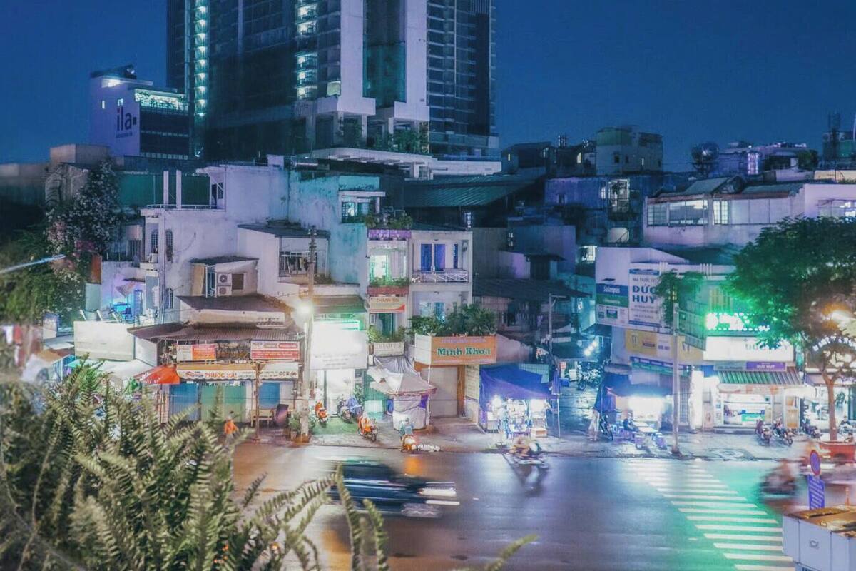 A city street at night with buildings, shops, and a crosswalk.