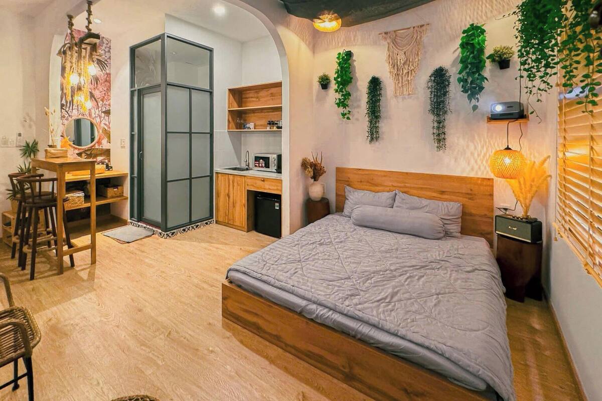 A bedroom with a bed, a desk, a chair, and a small kitchenette.