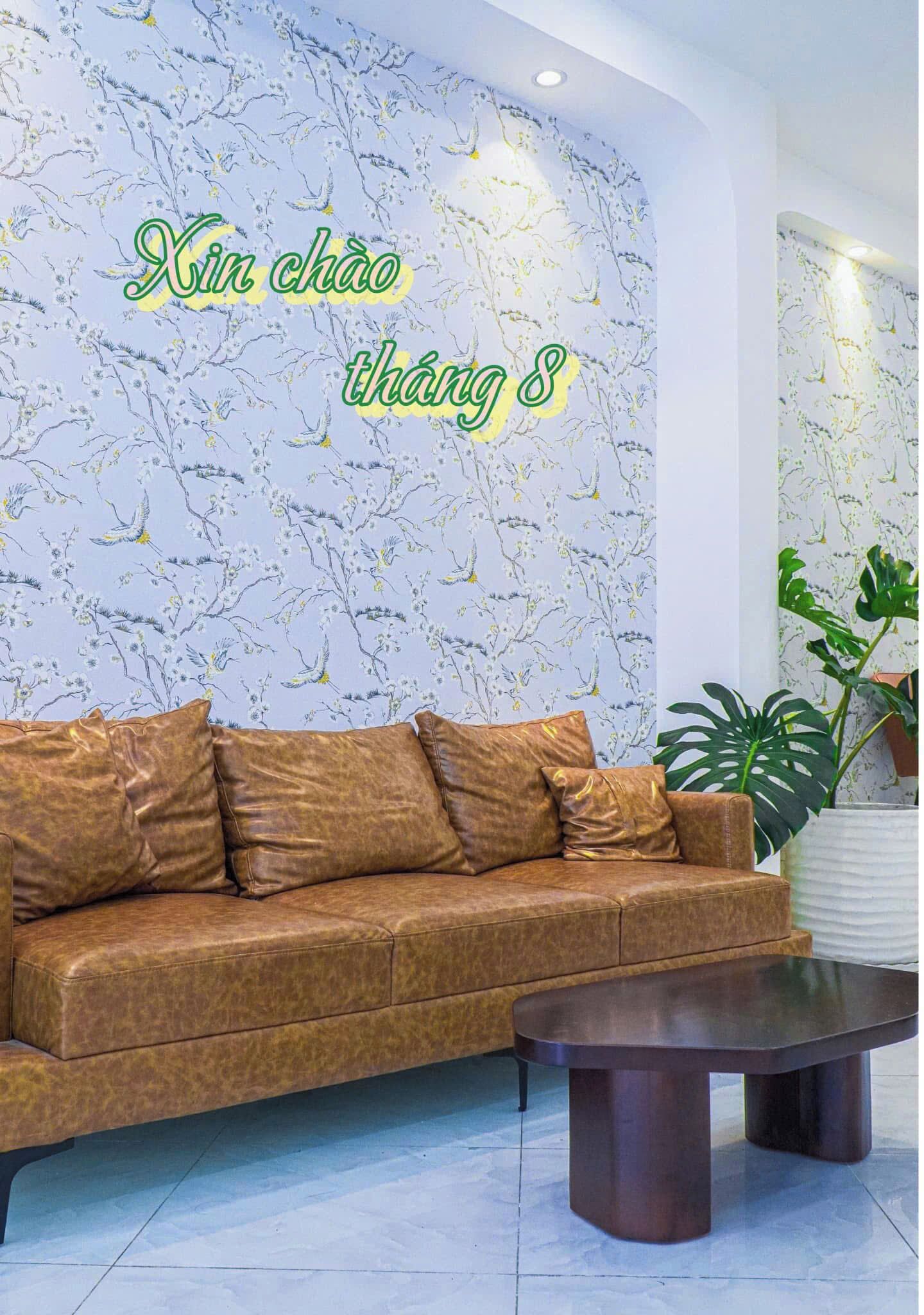 A room with a brown leather sofa, a dark wooden coffee table, and a floral wallpaper.