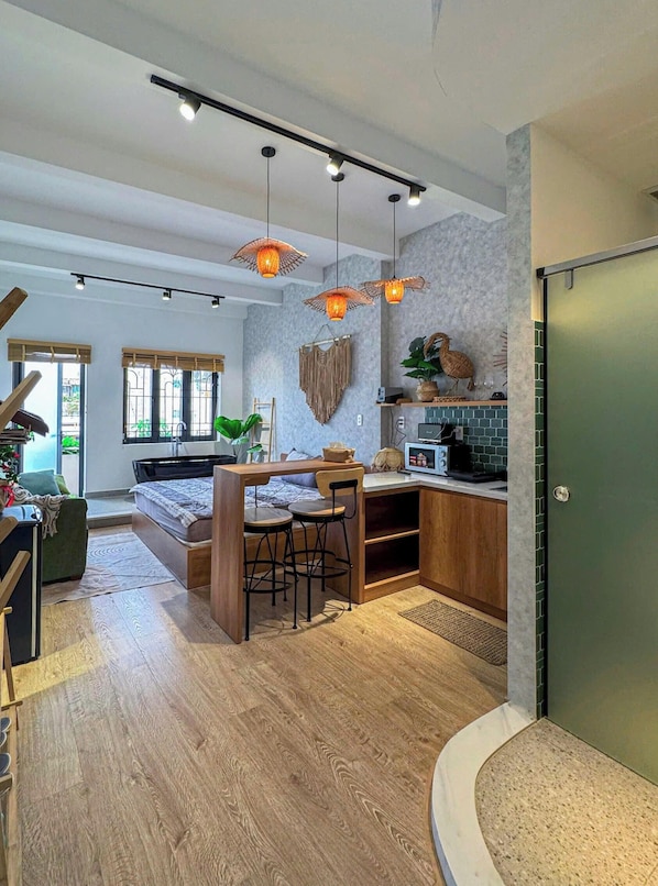 A modern kitchen with a dining area, wooden flooring, and pendant lighting.