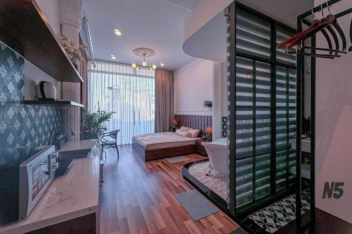 A modern bedroom with a bed, bedside table, and a view through a glass door.