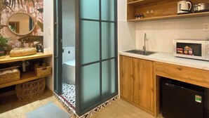 A compact kitchen with a sliding door, wooden shelves, a microwave, and a sink. - HHome Tran Dinh Xu (Ho Chi Minh City)