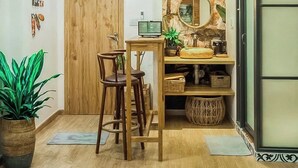 A room with a wooden door, a small table with two chairs, a mirror, and a shelf with various items. - HHome Tran Dinh Xu (Ho Chi Minh City)