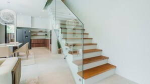 Un intérieur moderne comprenant un escalier, un coin repas et une cuisine.