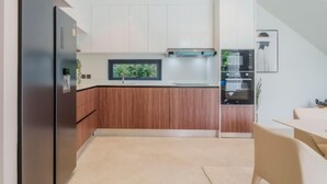 Une cuisine moderne dotée d’un four encastré, d’une fenêtre au-dessus de l’évier et d’un coin repas avec une table et des chaises.