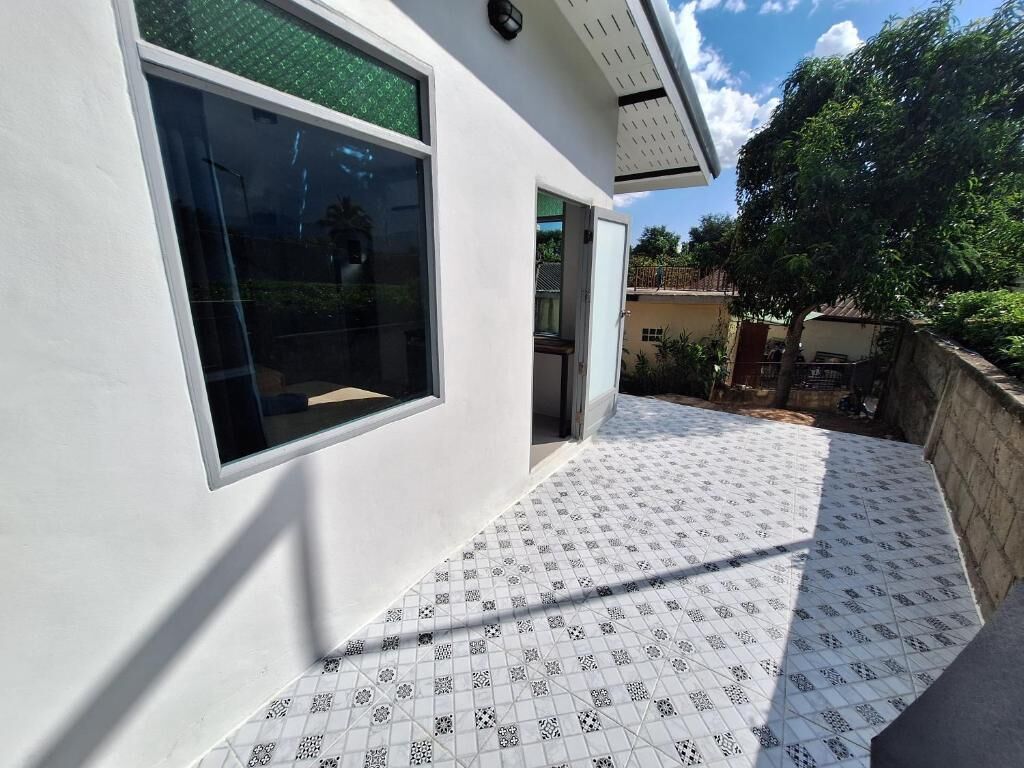 A modern building with large windows, a patterned tiled patio, and a visible door.