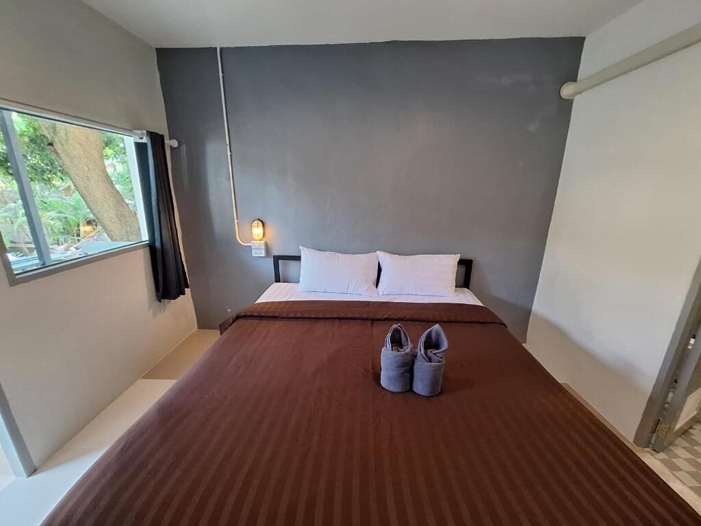 A bedroom with a bed, a window, a nightstand, and a lamp.