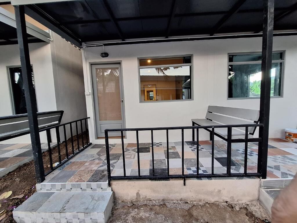 A covered outdoor area with a bench, a door, and a window.