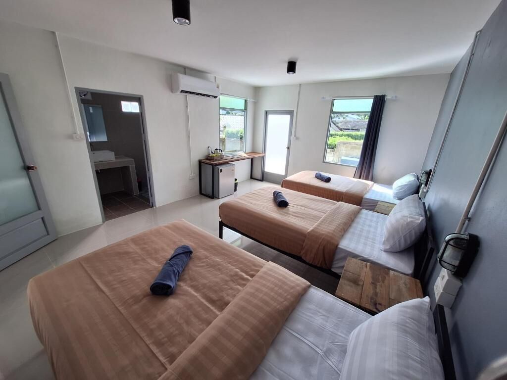 Habitación de hotel con tres camas, un escritorio y una ventana.
