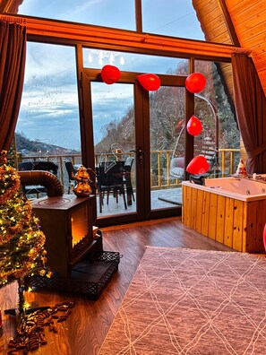 A cozy room with a fireplace, a wooden bench, a Christmas tree, and a view of the outdoors.