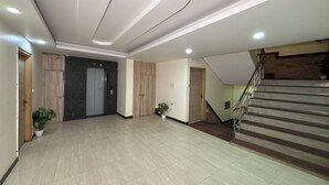 A spacious lobby with a tiled floor, a staircase, and a door leading to an elevator. - HOTEL ROYAL RESIDENCY  (New Delhi)