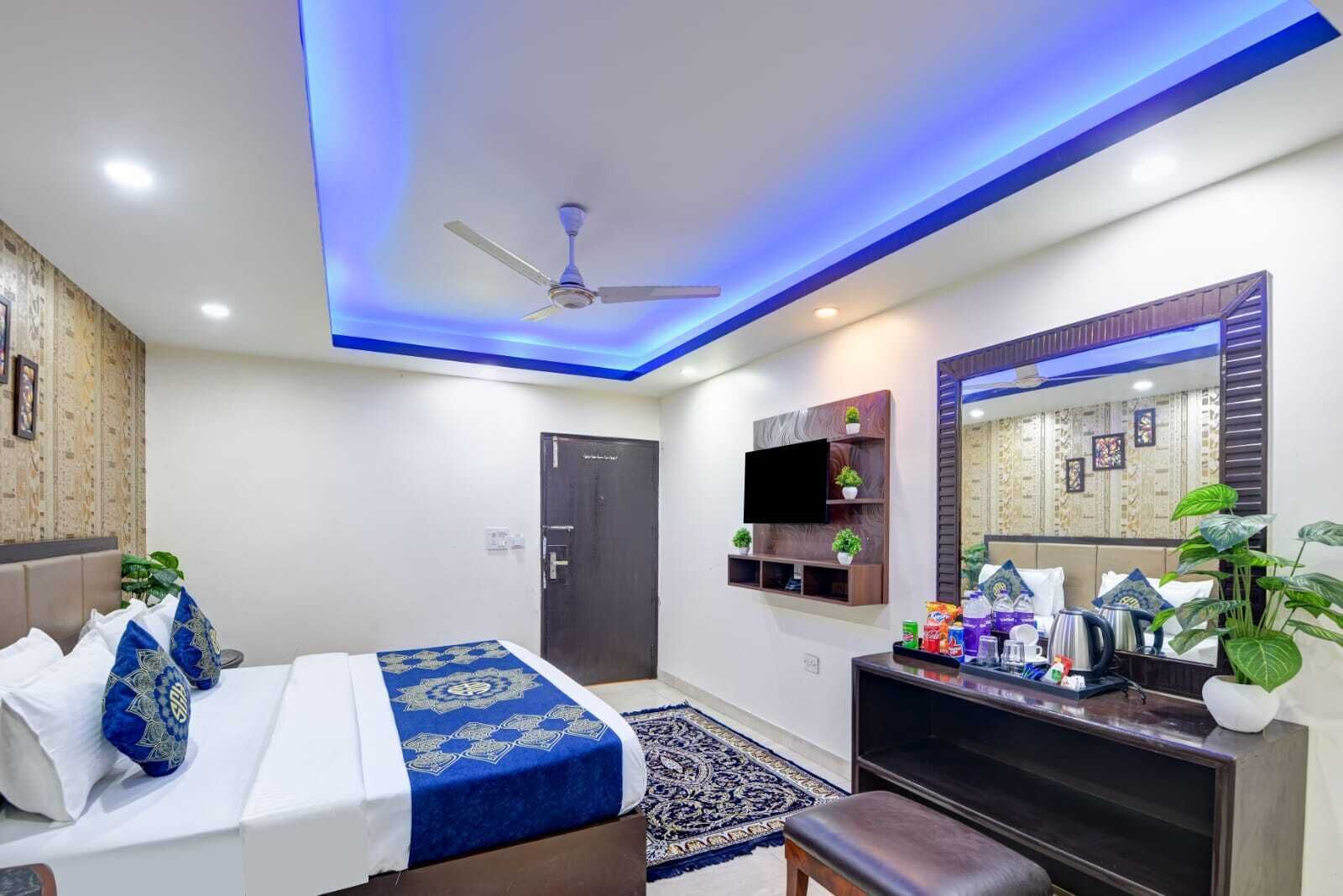 A hotel room with a bed, a desk, a television, a ceiling fan, and a door.
