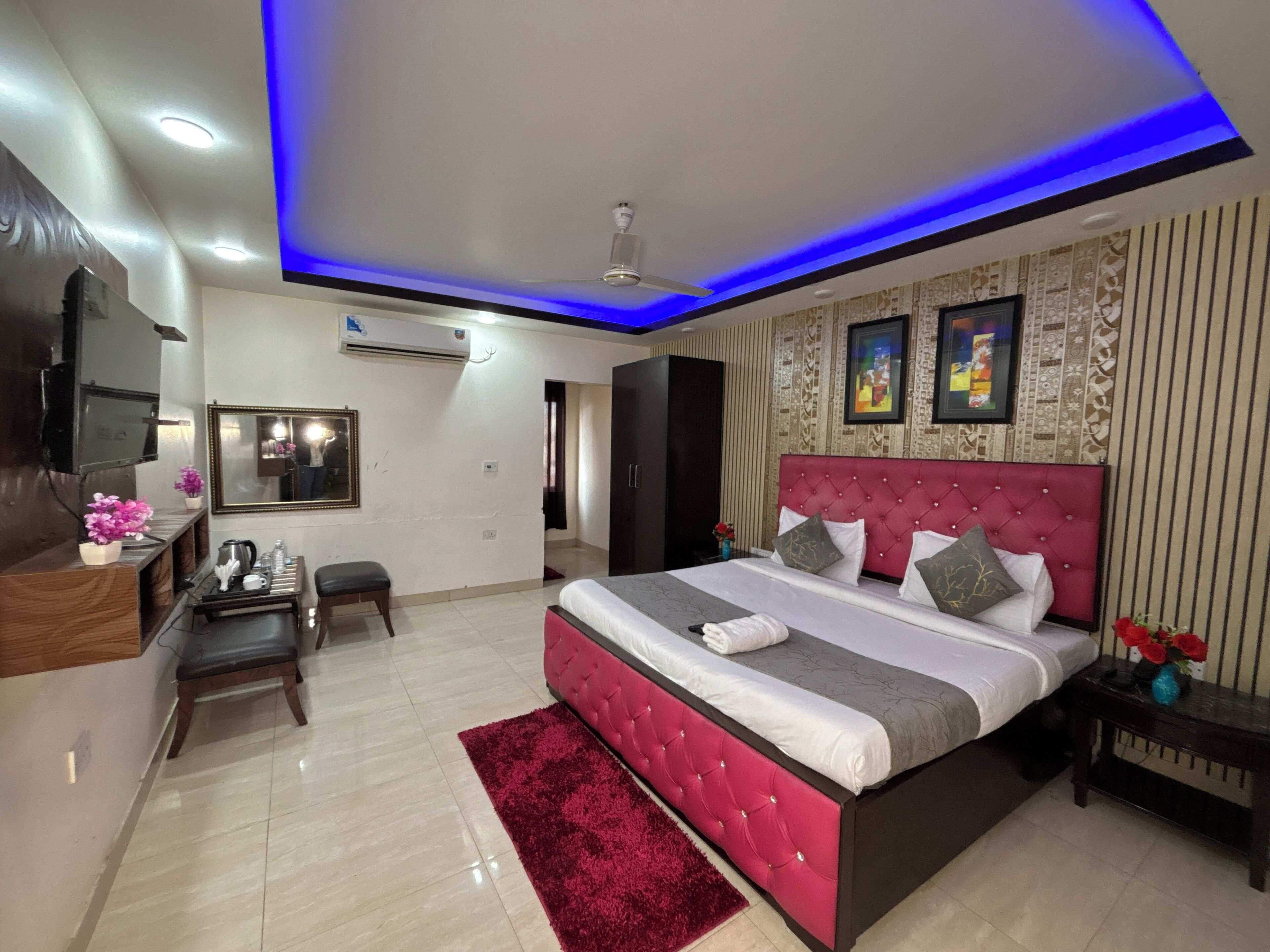 Un dormitorio moderno con una cama grande, televisión, escritorio y una alfombra roja.