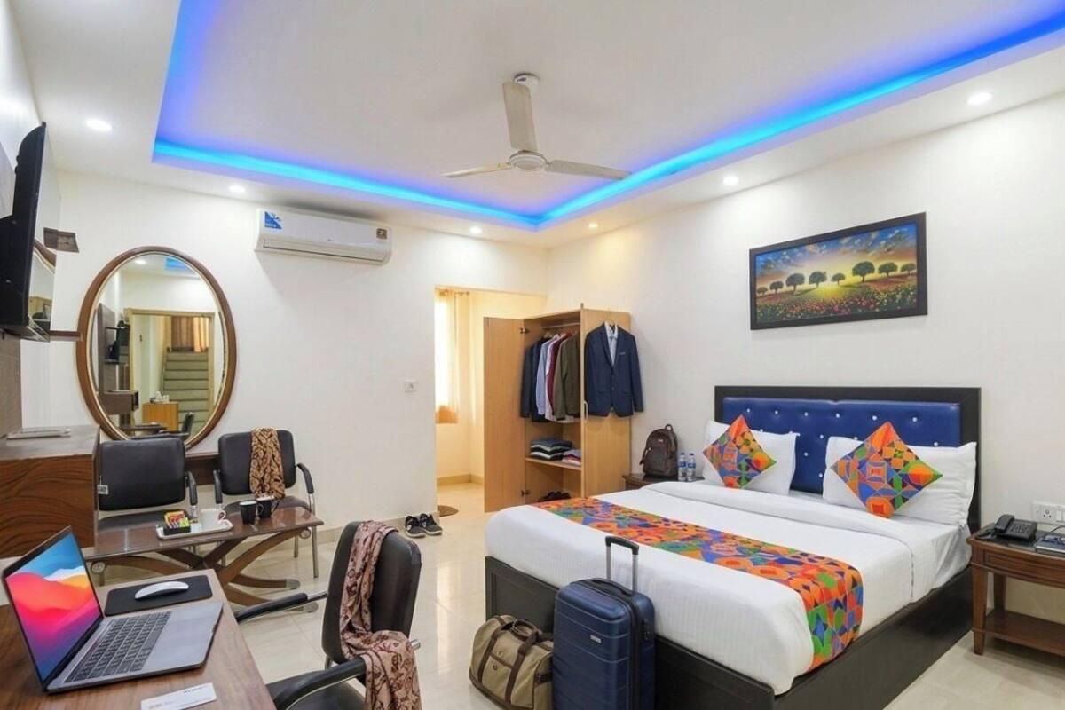 Una habitación de hotel con cama, escritorio, silla, armario y ventilador de techo.