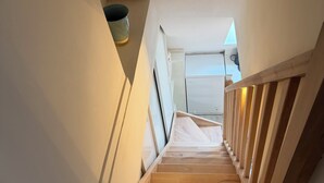 Eine Holztreppe führt zu einem Schlafzimmer mit Dachfenster.