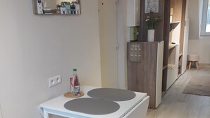 Eine moderne Küche mit einem weißen Tisch, Holzstühlen, einem Kühlschrank und einer Mikrowelle.