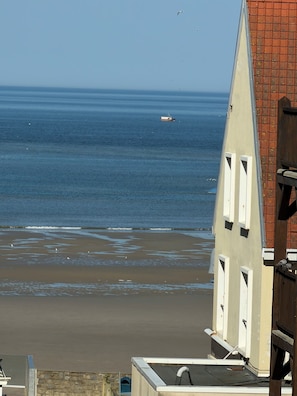 A coastal view with a beach, a small boat, and a building with a sloped roof and windows. - Stay in a 3-star apartment for 2–3 people (Le Portel)