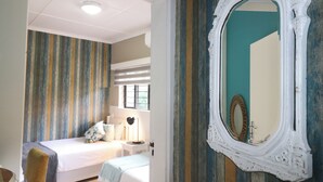Et soveværelse med en seng, et natbord, en lampe og et spejl på væggen.