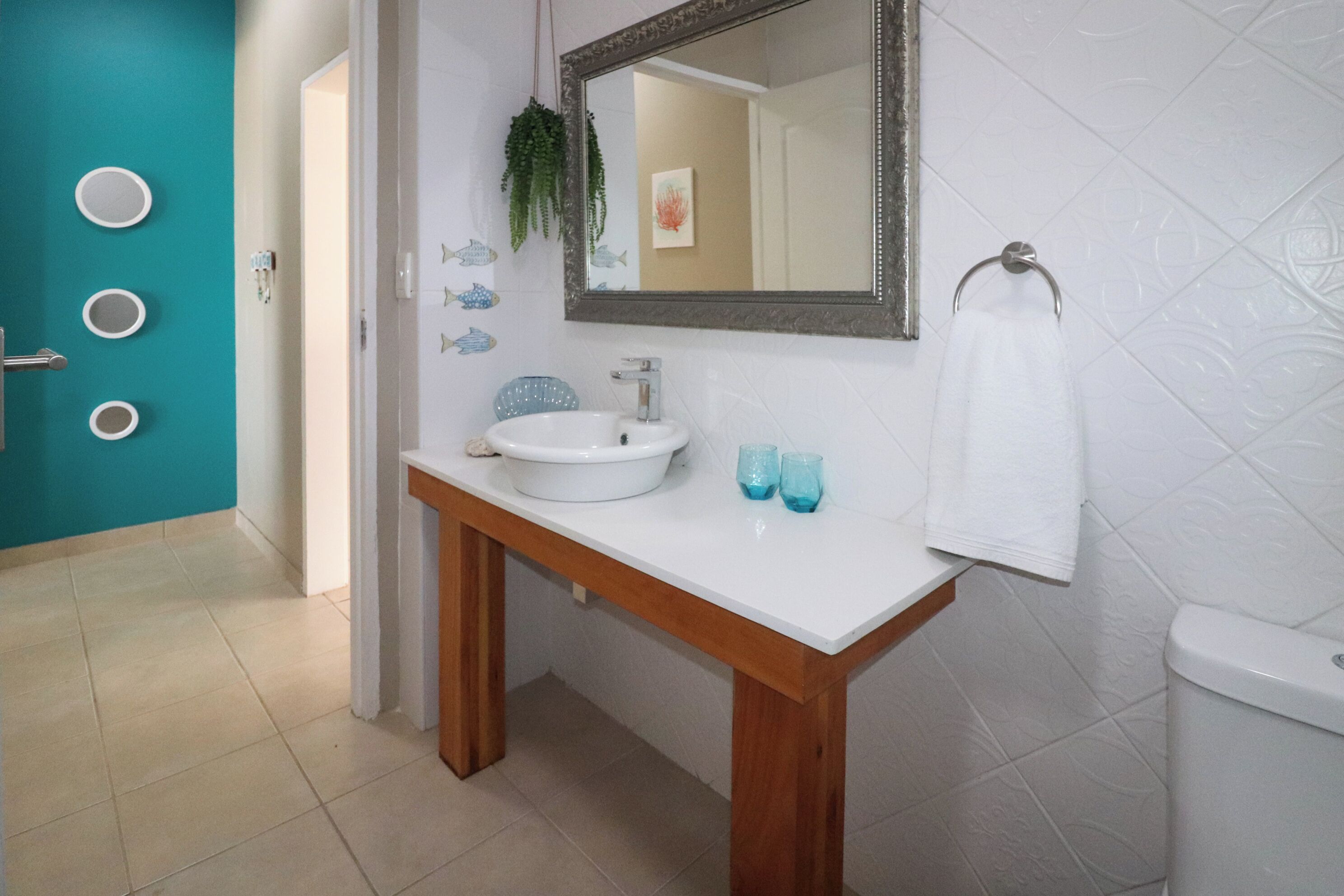 A bathroom with a white sink, wooden vanity, and a mirror.