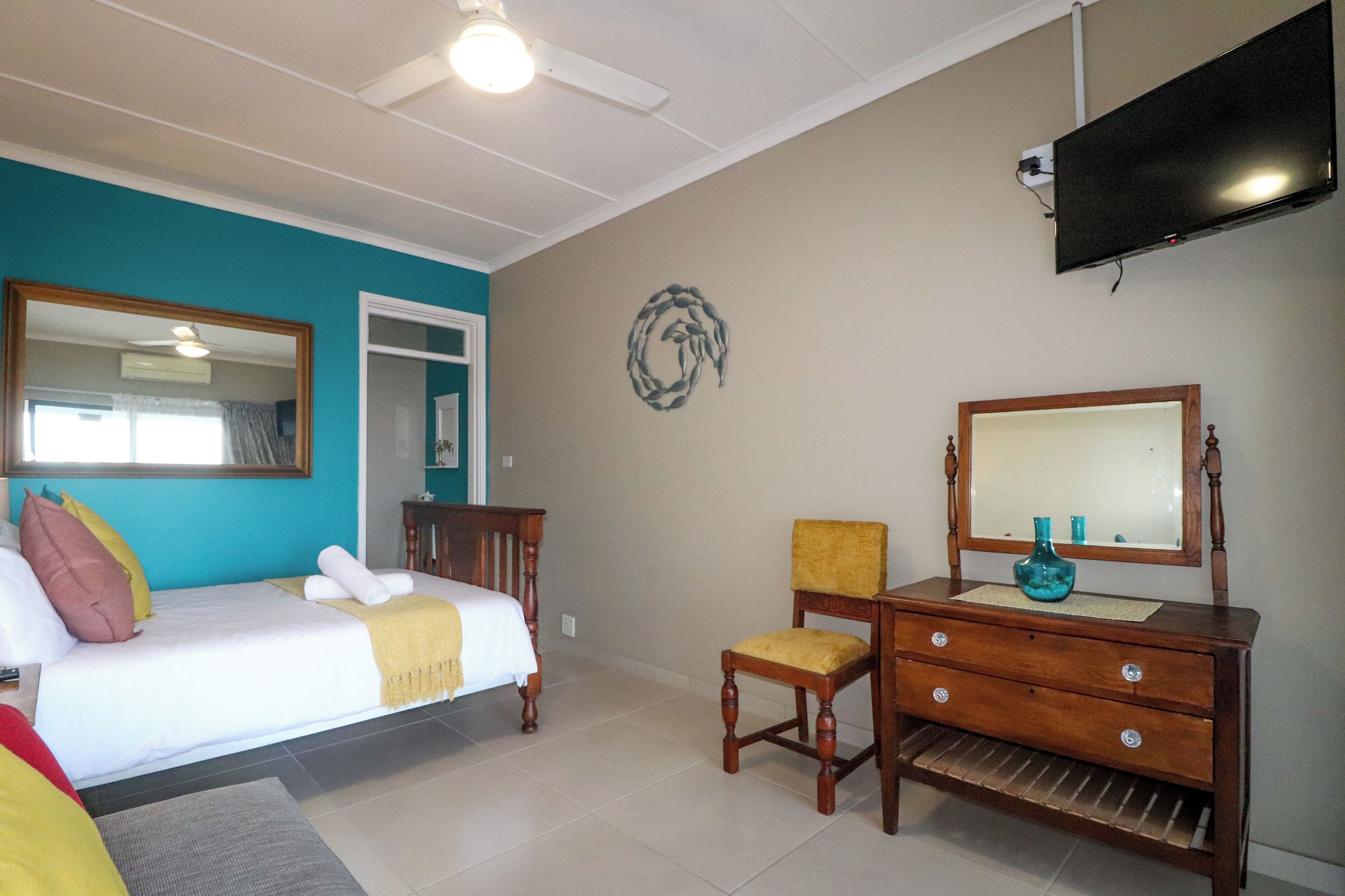 A hotel room with a bed, a dresser, a chair, a television, and a mirror.