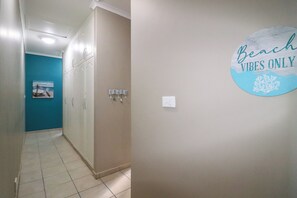 A hallway with a blue wall, a white cabinet, and a sign on the wall. - 7 Sands (Ballito)