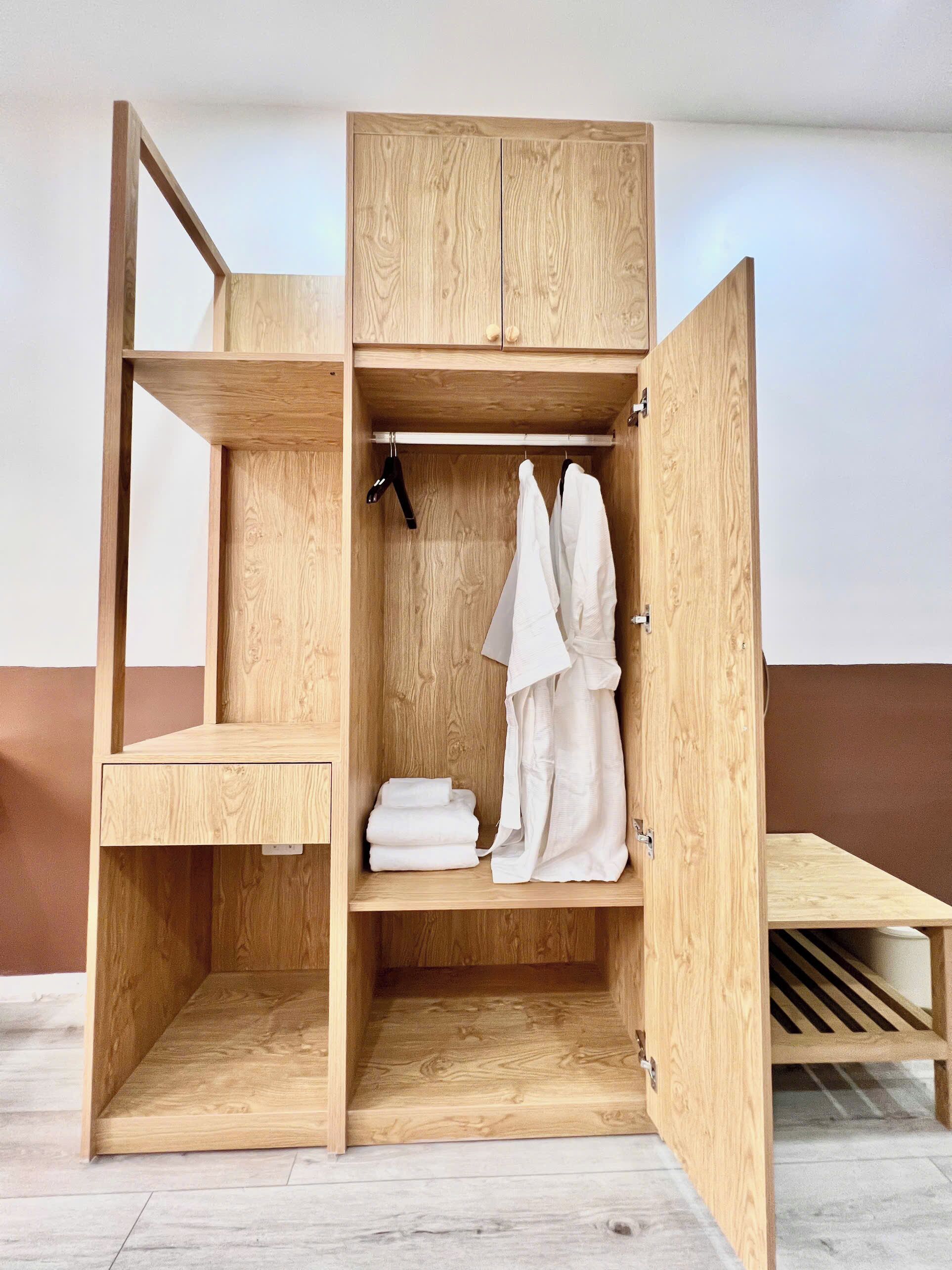 Un armario de madera con varios compartimentos, que incluye espacio para colgar y estantes.