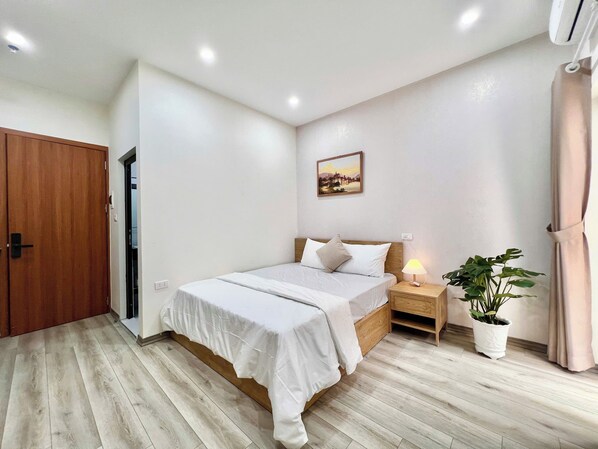Une chambre à coucher avec un lit, une table de chevet, une lampe, une plante en pot et un tableau au mur.