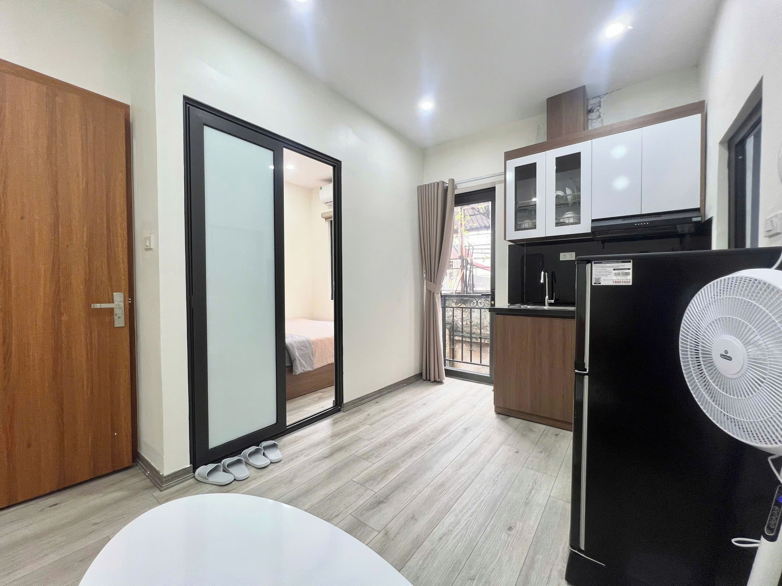 Una cocina compacta con refrigerador, microondas y alacenas.