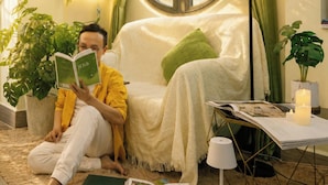 A cozy reading nook with a person reading, a round window, a lamp, and green curtains. - La Yen Homes (Ho Chi Minh City)