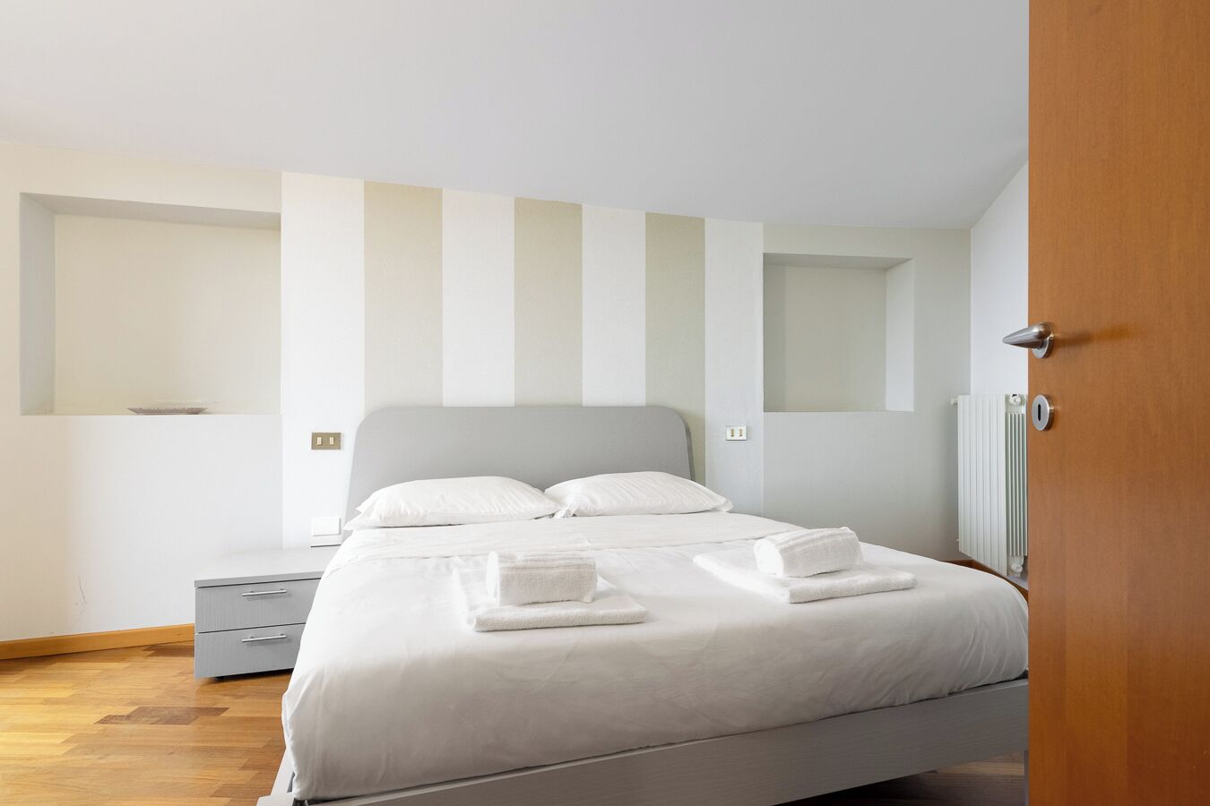 Una habitación de hotel moderna con una cama, mesita de noche y un radiador.