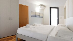 A bedroom with a bed, a wardrobe, a painting, and a door. - Lemon House 2 by Wonderful Italy (Gardone Riviera)