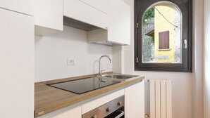 A modern kitchen with a built-in sink, wooden countertop, and a window with a view of a yellow building. - Lemon House 2 by Wonderful Italy (Gardone Riviera)