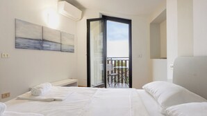 A hotel room with a bed, a bench, a balcony with a table and chairs, and artwork on the wall. - Lemon House 2 by Wonderful Italy (Gardone Riviera)