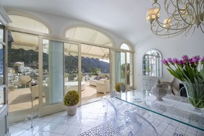 A spacious balcony with a clear view of the mountains, a glass table with chairs, and a vase of flowers. - Villa Il Panorama (Positano)