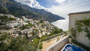 Un pueblo costero con edificios, una piscina y vistas al mar.