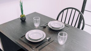 A dining table set with plates, cutlery, and glasses, with a small plant on the table.