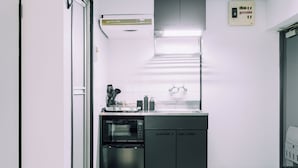 A compact kitchen with a built-in oven, a dishwasher, and a small countertop with a coffee machine.