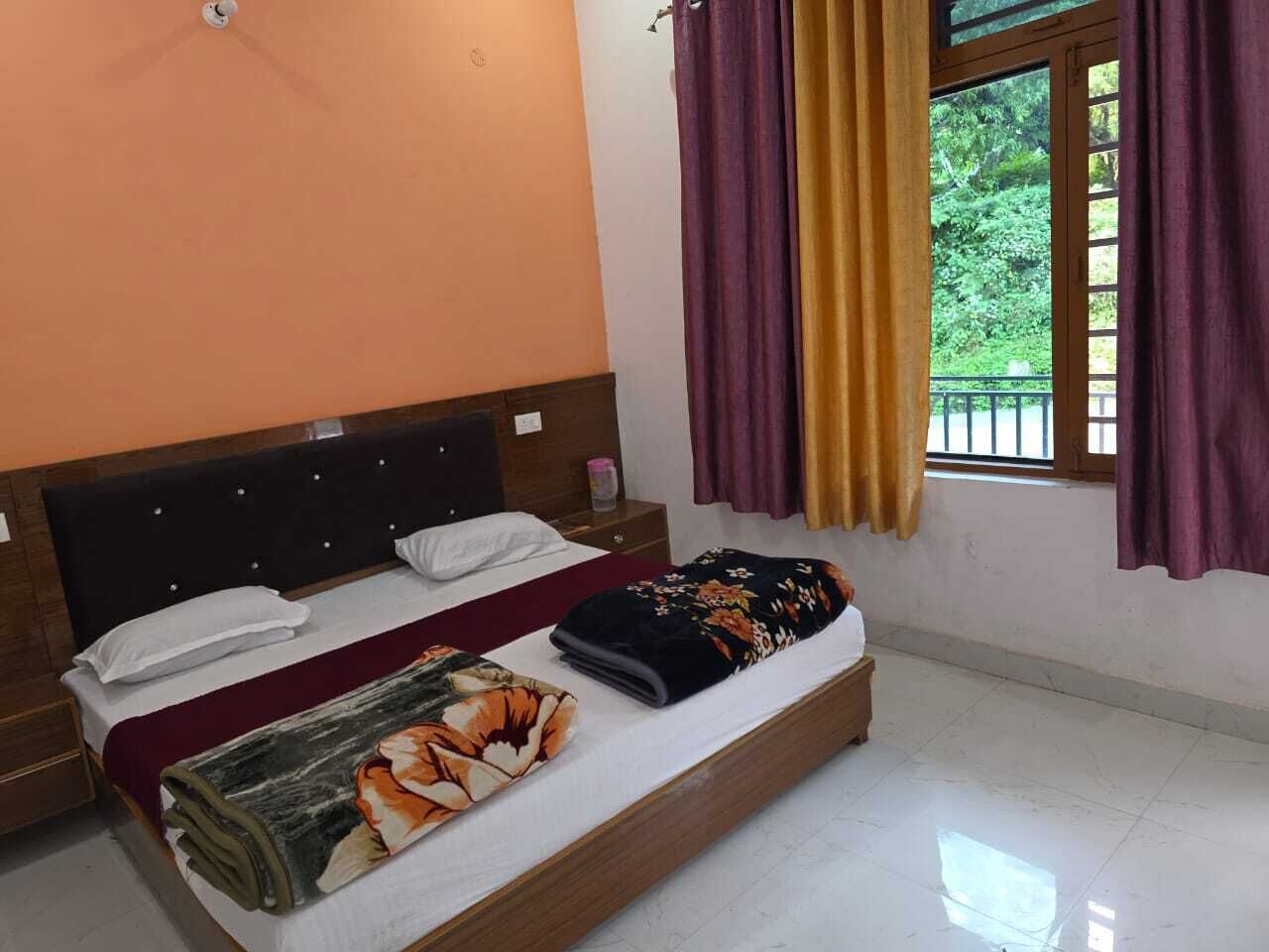 A double bed with a headboard, a nightstand, a window with curtains, and a view of greenery outside.