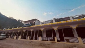 A hotel named 'Hotel Moon Rise' with a balcony, a parking area, and a mountainous backdrop. - Hotel Moon Rise (Ukhimath)